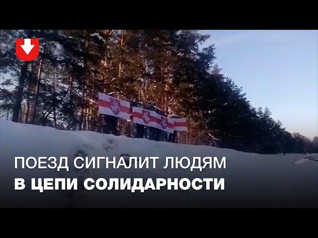 Поезд сигналит людям, которые стоят в цепи солидарности возле железной дороги