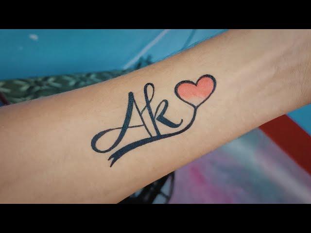 Drawing temporary tattoo of A K letter tattoo with pen - AK couple letter tattoo design ideas