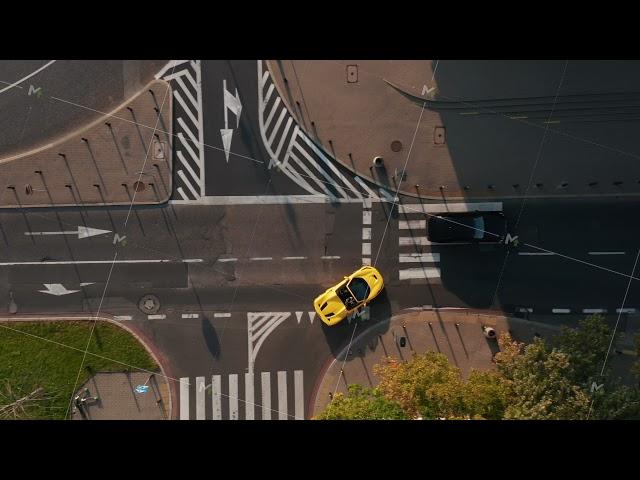 Aerial birds eye overhead top down view of yellow convertible car turning on main road. Late