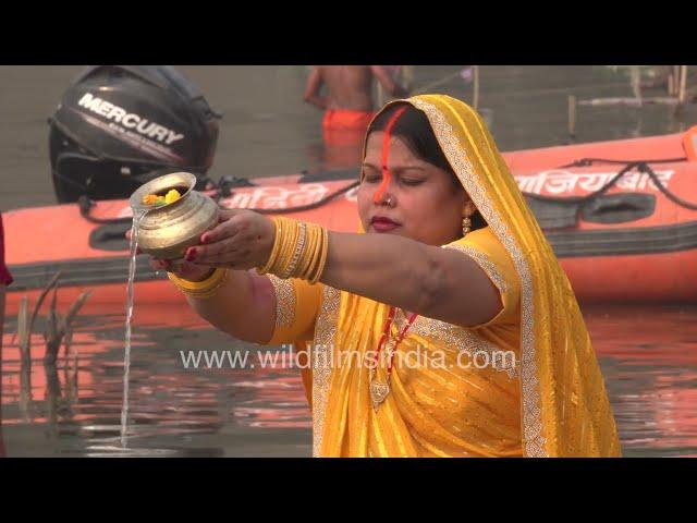 Woman in Yellow colored saree offering water to the setting sun Chhath Puja Yamuna Ghat Noida