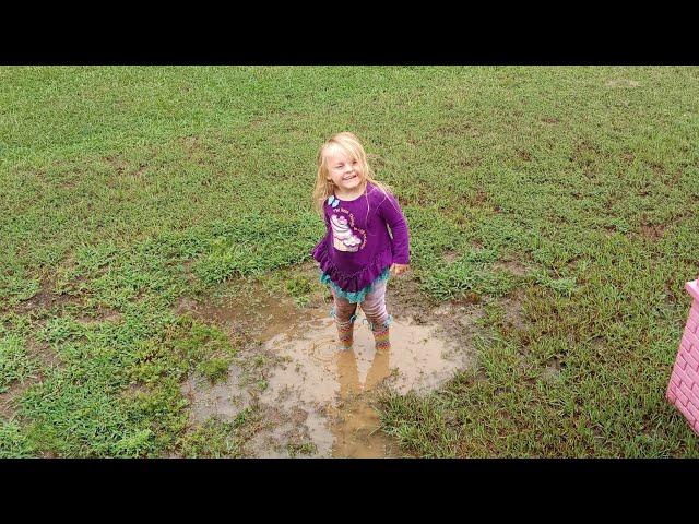 Splashing in muddy puddle with her rainbow rubber boots!  