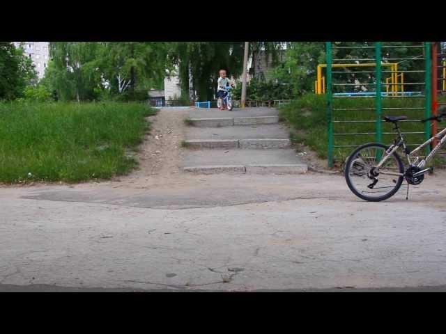 Three years old boy riding running bike down the stairs