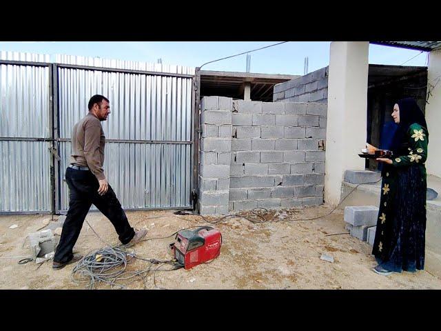 Installing a yard door for Sakineh's house by a welder