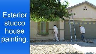 Painting a stucco house exterior.