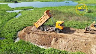 Start new road building with shantui bulldozer and shacman dump truck unloading soil