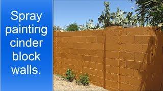 Spray painting exterior cinder block walls.