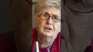 Grandma In Pink Sweater Comments About Seat Decorations On Wall