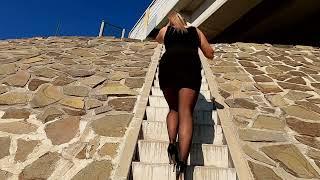 Walking up the stairs in high heels, short skirt, black nylons.