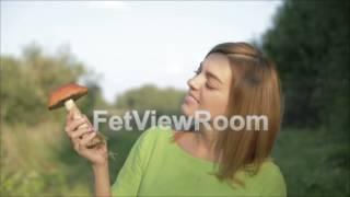 Beautiful young girl looking at the orange-cap boletus in hand