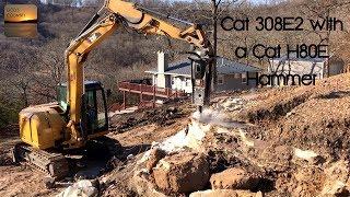 Cat 308E2 Excavator breaking rock with a Cat H80E hammer