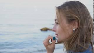 Portrait of tender girl who poses on camera, cute smiling and stands against blue sea and sky at