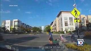 A little girl is almost hit by a car while trying to cross the street