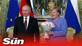 Vladimir Putin gives Angela Merkel flowers as they meet in Kremlin