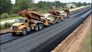 A road construction with a gravel spreading truck and dump trucks work together to lay down gravel.