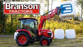 Branson 5025C moves round bales with front loader