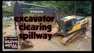 excavator clearing of spillway , heavy metal operator