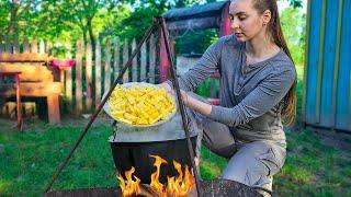 Ukrainian girl cooks Ukrainian Green Borscht in the village, yard work, countryside aesthetics