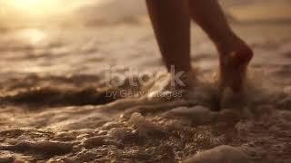 Beautiful Scene Of A Low Section Of Woman Walking On Ocean Beach At Sunset