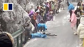 Mother and daughter slide down icy mountain road in China