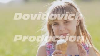 Beautiful blond little girl eats ice-cream in the summer against the background of a wheat field