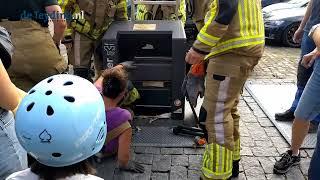 Warmondse brandweervrouw klimt uit papiercontainer waar een portemonnee in was gevallen