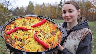 Ukrainian woman cooks tradition Pilaf on an open fire in the village