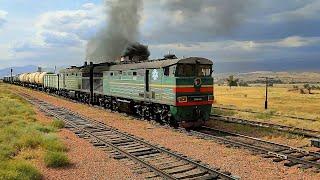 Diesel locomotive 2TE10V-4661 with a freight train, fire, black smoke passes the Dzhil-Aryk station.