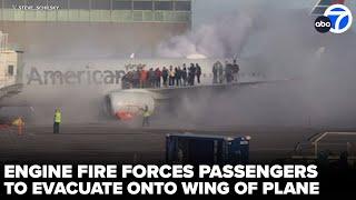 Passengers evacuate onto wing of plane after engine catches fire at airport