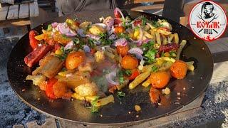 Cooking a delicious dish on a giant metal frying pan KOZAK GRILL