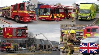 Many fire trucks on scene and firefighters in action at a warehouse fire