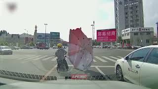 Mopedist catches flying umbrella