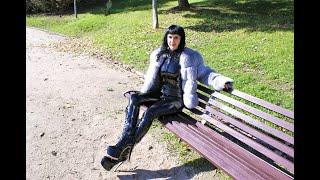 Victoria Devil. Shiny black latex catsuit, knee high heeled boots walking in public in the park.