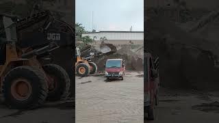 bulldozers load sand into small trucks 